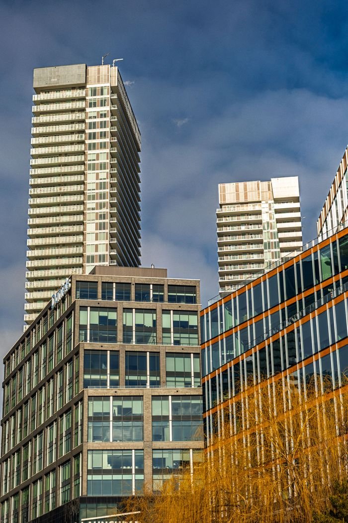 Contemporary high-rise buildings against a cloudy blue sky in Ontario, showcasing modern architecture.